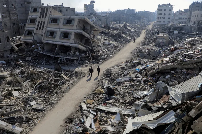 Palestinians walk past destroyed buildings in Jabalia refugee camp in northern Gaza that has been destroyed by Israeli occupation forces (Reuters photo)