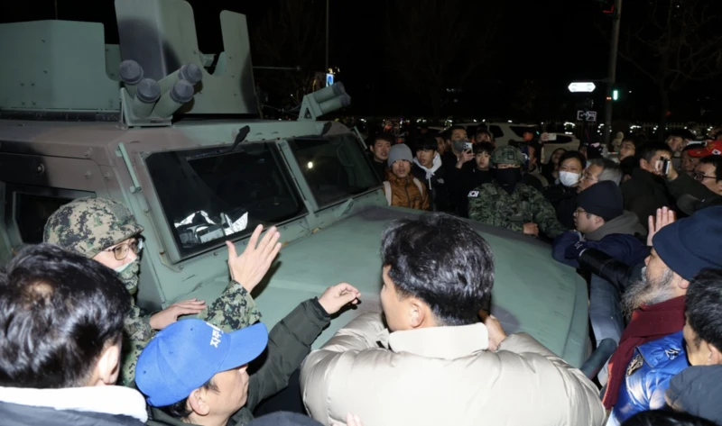 South Korean army troops move away from the Parliament building amid cheers by demonstrating crowds. 3 December 2024. (Reuters photo)