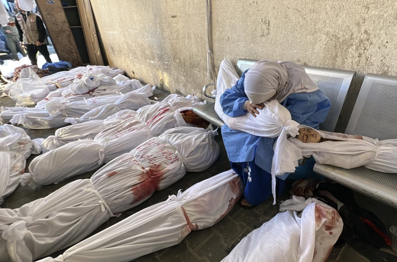 A Palestinian woman reacts over the body of a child as she sits by bodies of Palestinians killed by Israeli airstrikes on Jabaliya refugee camp, at the Indonesian hospital, northern Gaza Strip, Nov. 18, 2023. (AP Photo)